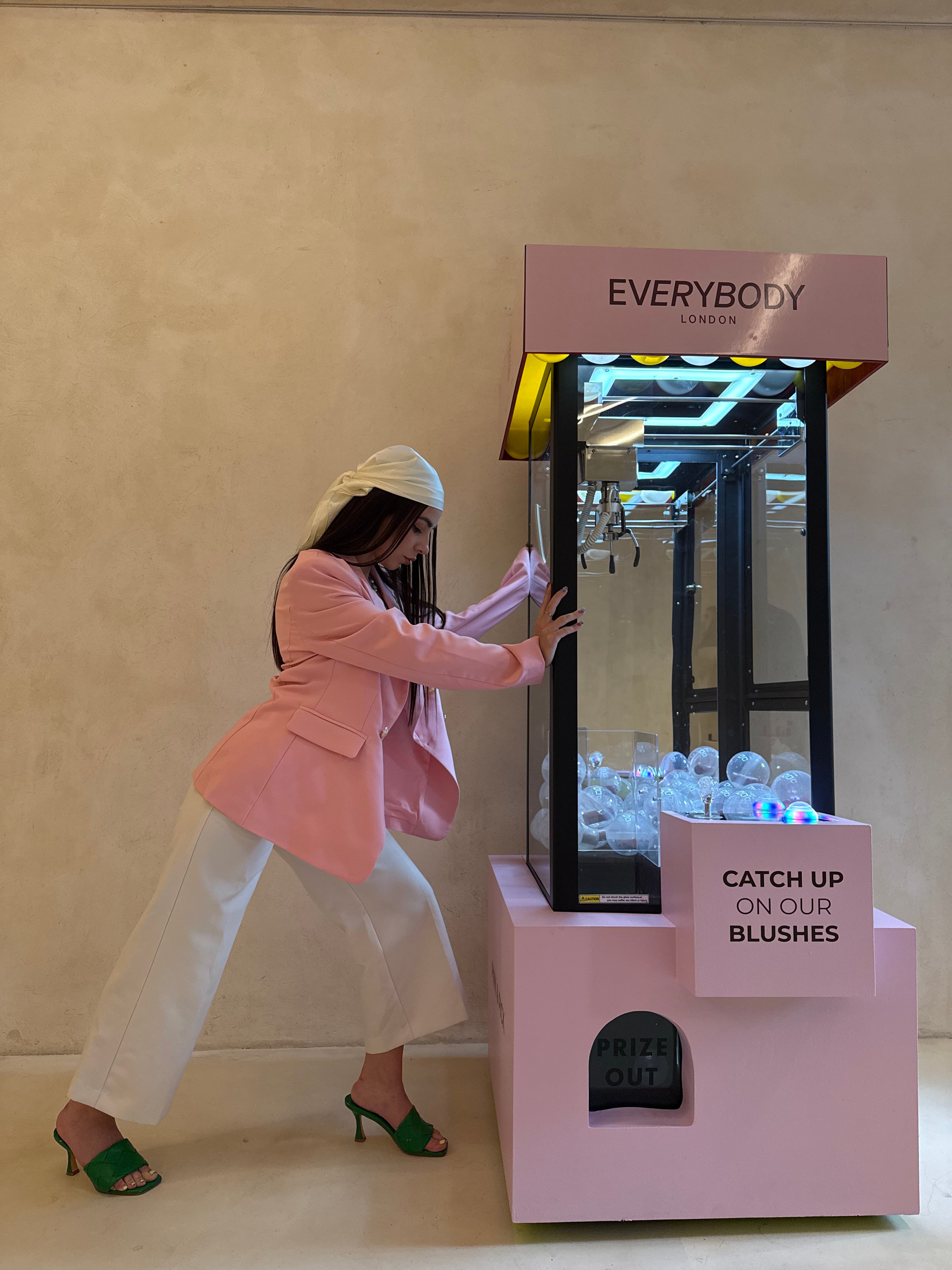 Lizaveta in a pink blazer pushing a pink Everybody London claw machine