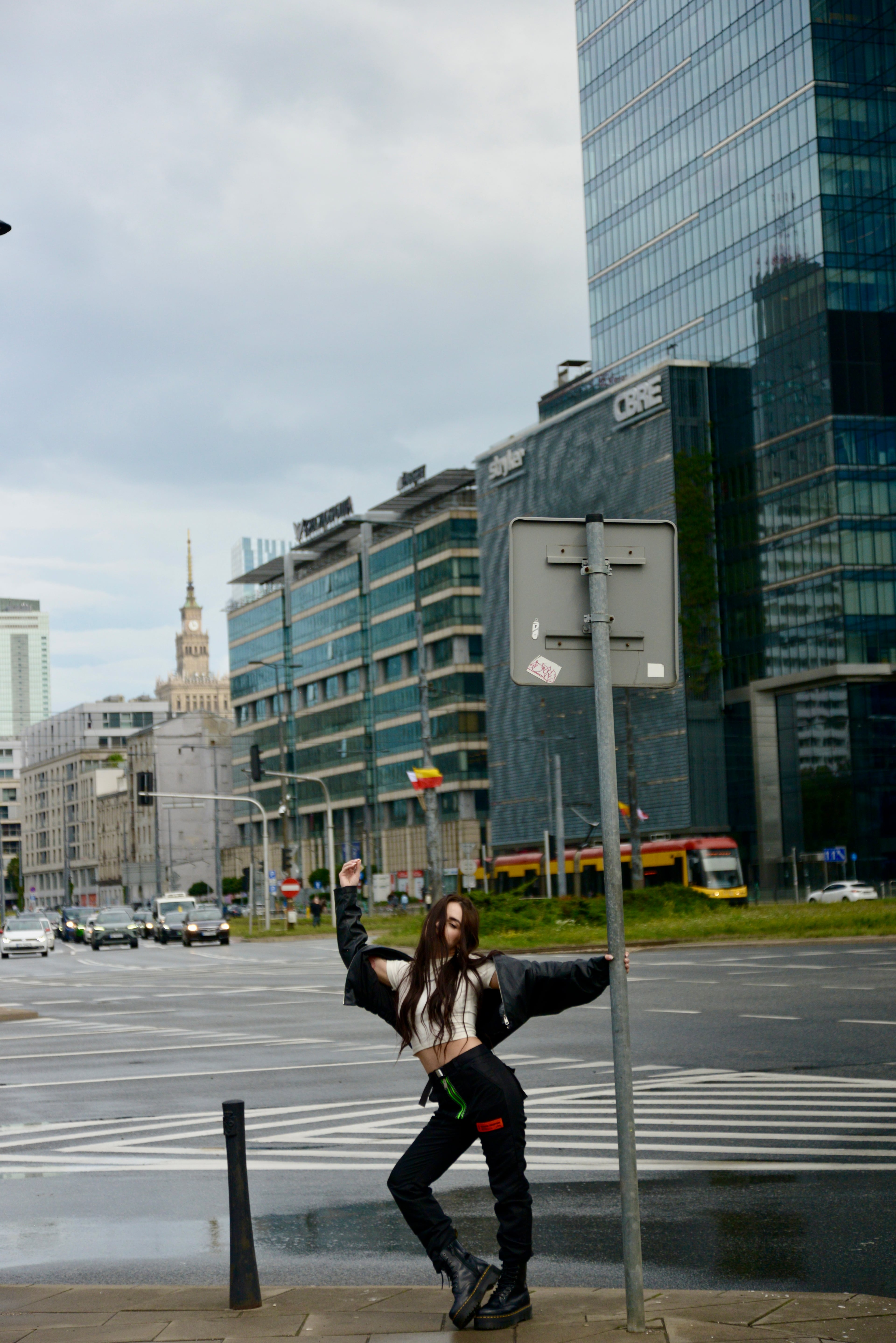 Lizaveta posing at a Warsaw street crossing with the Palace of Culture and glass towers behind