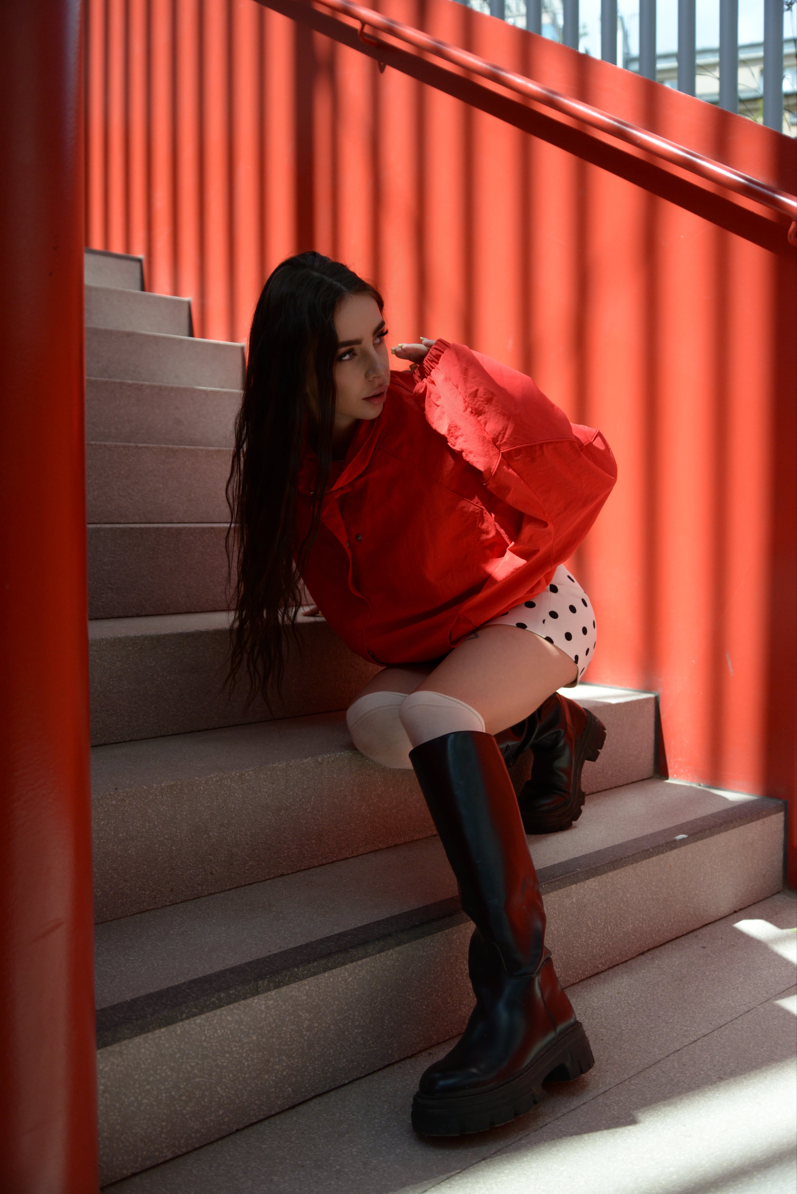 Lizaveta seated on a staircase against a red slatted wall
