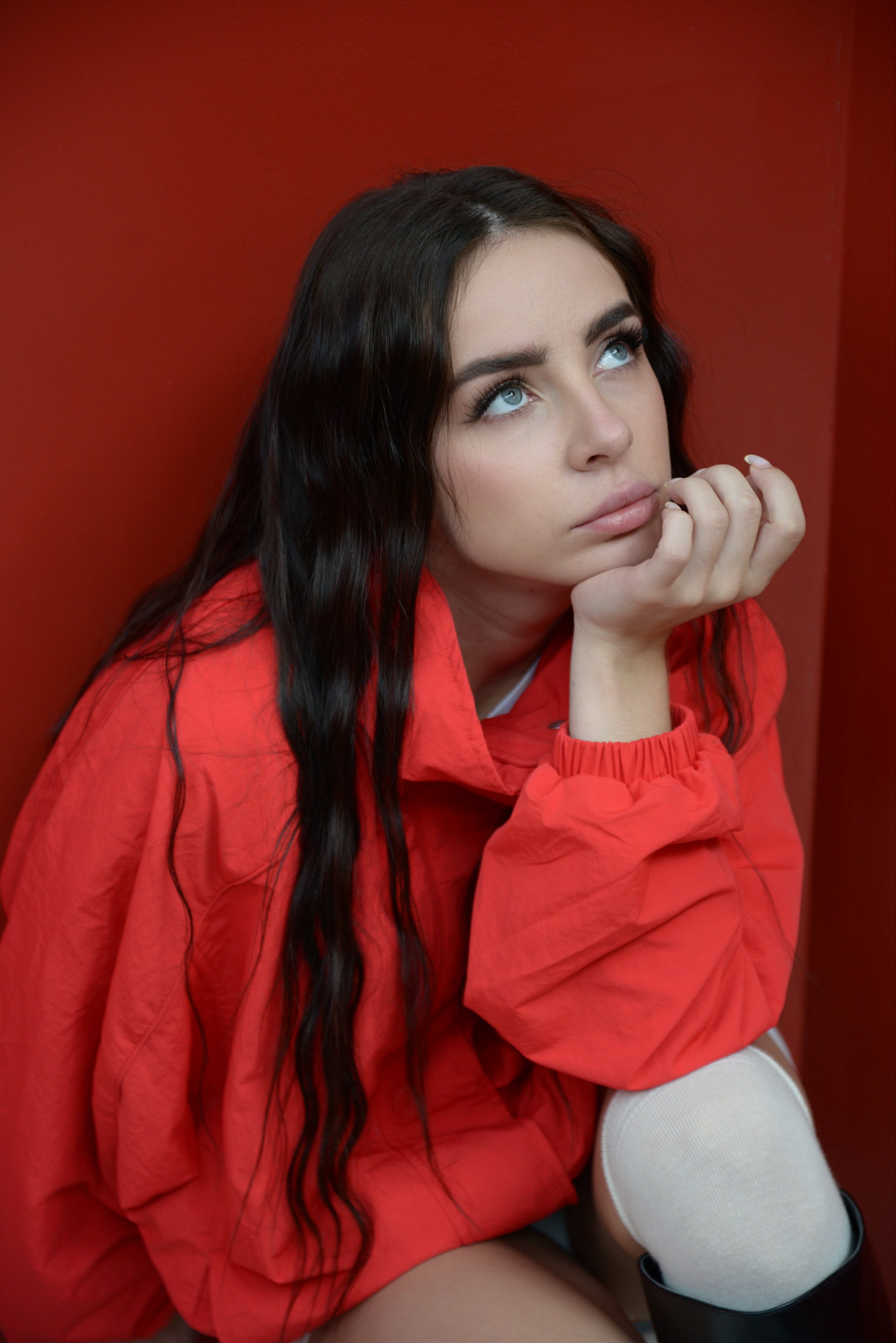 Close portrait of Lizaveta in a red jacket against a red wall, chin resting on her hand